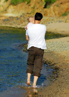 Man walking on a beach holding baby
