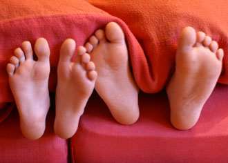 Men and women feet in bed