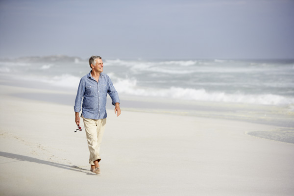 Middle age man walking along the beach thinking